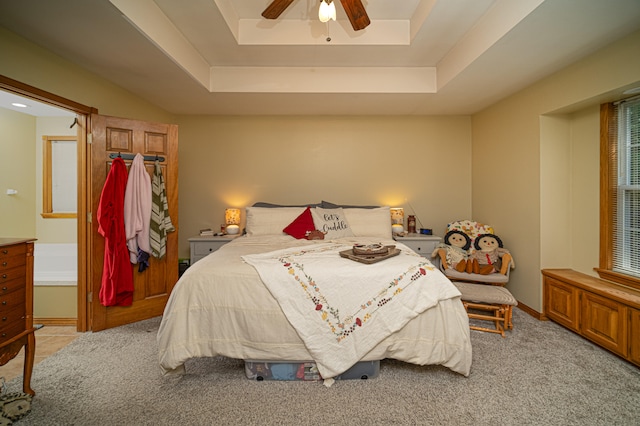 bedroom featuring light carpet, ceiling fan, and a raised ceiling