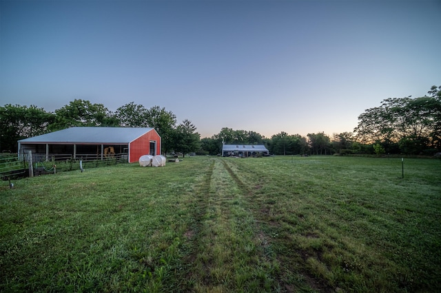 yard at dusk with a rural view and an outdoor structure