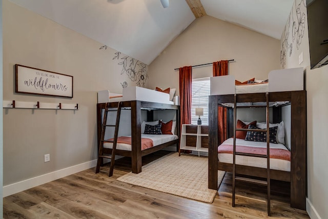 bedroom featuring hardwood / wood-style floors, vaulted ceiling with beams, and ceiling fan