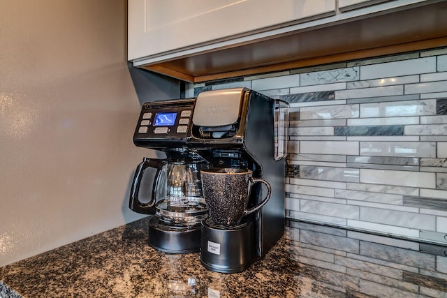 room details with tasteful backsplash, dark stone countertops, and white cabinetry