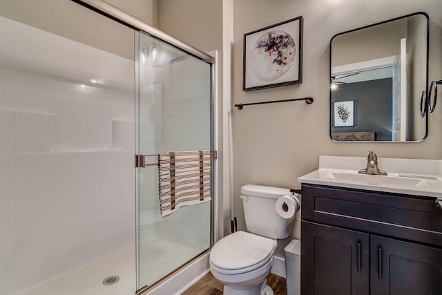 bathroom with hardwood / wood-style flooring, vanity, a shower with door, and toilet