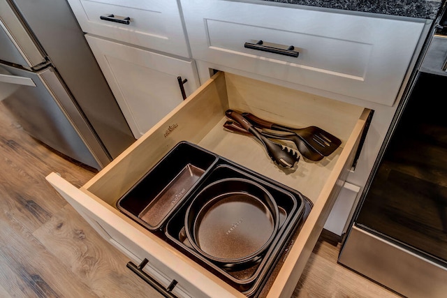 room details with light hardwood / wood-style flooring, stainless steel range oven, and white cabinetry