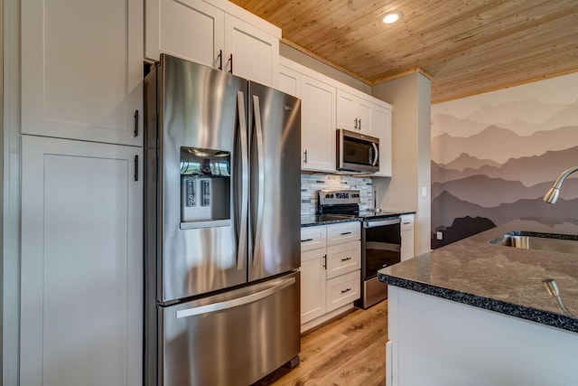 kitchen with stainless steel appliances, white cabinets, sink, light hardwood / wood-style floors, and dark stone counters