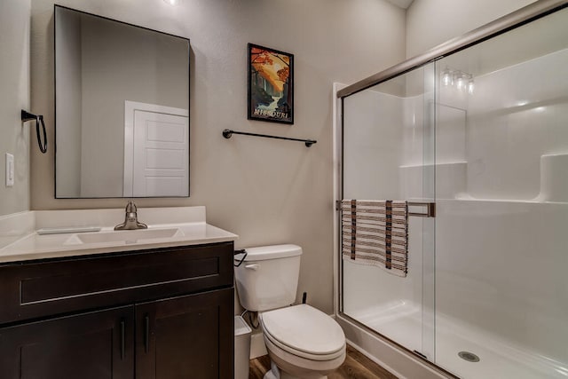 bathroom featuring walk in shower, vanity, hardwood / wood-style floors, and toilet