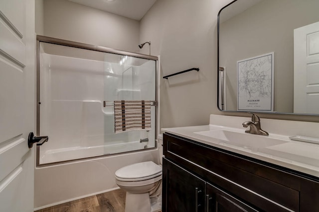 full bathroom featuring bath / shower combo with glass door, wood-type flooring, vanity, and toilet