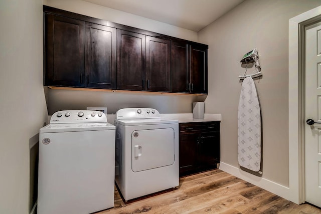 clothes washing area with cabinets, light hardwood / wood-style flooring, and washer and dryer