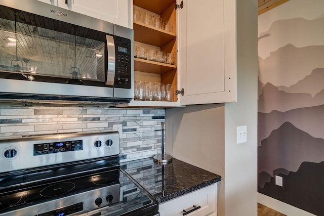 kitchen featuring tasteful backsplash, dark stone counters, white cabinets, and appliances with stainless steel finishes