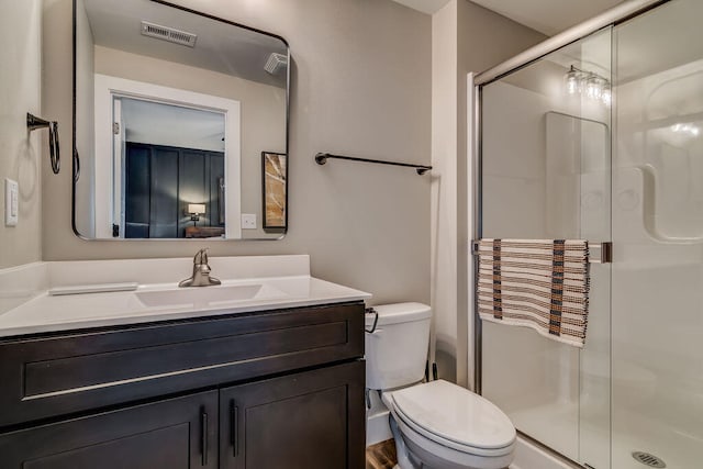 bathroom featuring an enclosed shower, vanity, and toilet