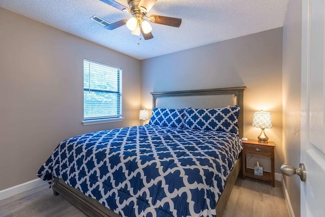 bedroom featuring hardwood / wood-style floors, a textured ceiling, and ceiling fan