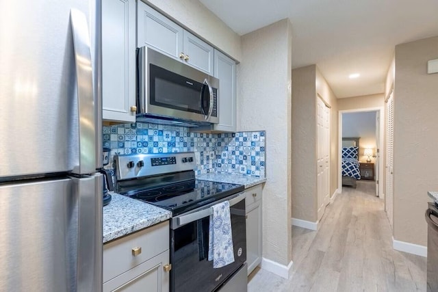 320 Turnberry Dr Unit 3, Branson, MO 65616 - kitchen featuring light wood-type flooring, stainless steel appliances, backsplash, baseboards, and light stone countertops