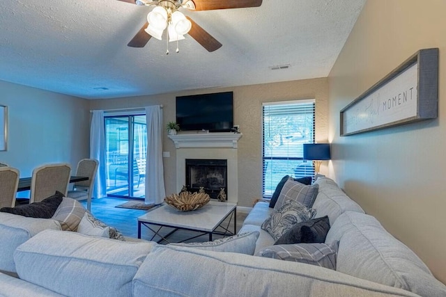 living room with ceiling fan, a textured ceiling, and wood-type flooring