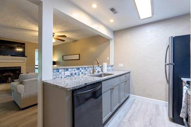 kitchen featuring light hardwood / wood-style floors, sink, light stone countertops, appliances with stainless steel finishes, and kitchen peninsula