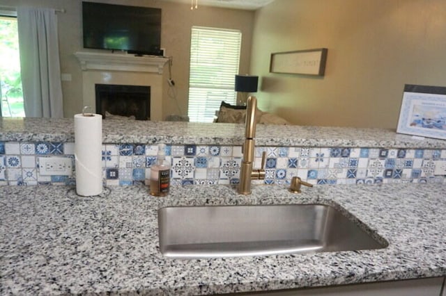 interior details featuring backsplash, sink, and light stone counters