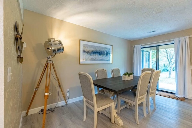 dining room with light wood-type flooring and a textured ceiling