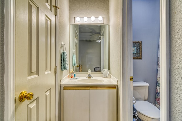 bathroom featuring a textured wall, vanity, and toilet