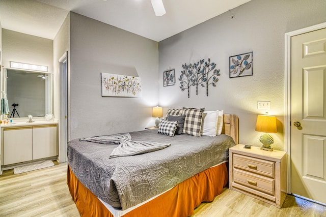 bedroom featuring a ceiling fan, a textured wall, and light wood-style flooring