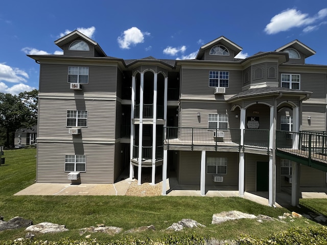 rear view of house with a wooden deck, a yard, and a patio