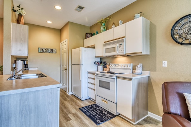kitchen with light wood-type flooring, visible vents, a sink, and white appliances