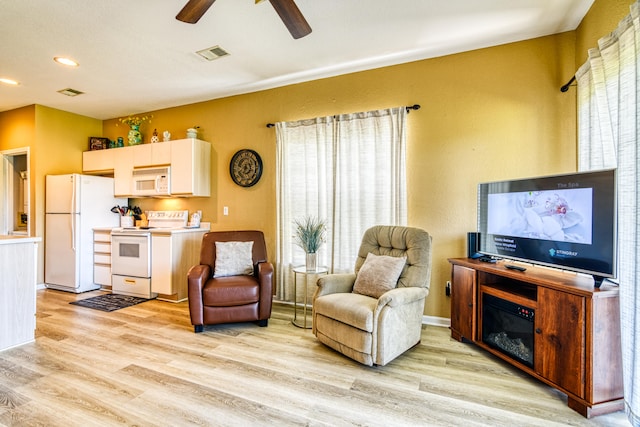 living room featuring ceiling fan, light hardwood / wood-style flooring, and a wealth of natural light