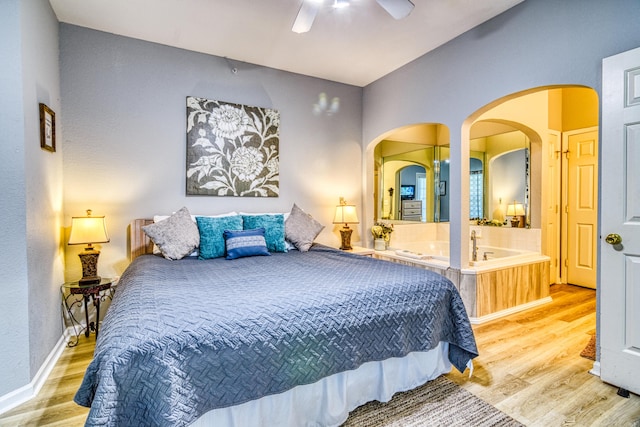 bedroom with baseboards, wood finished floors, arched walkways, and ceiling fan