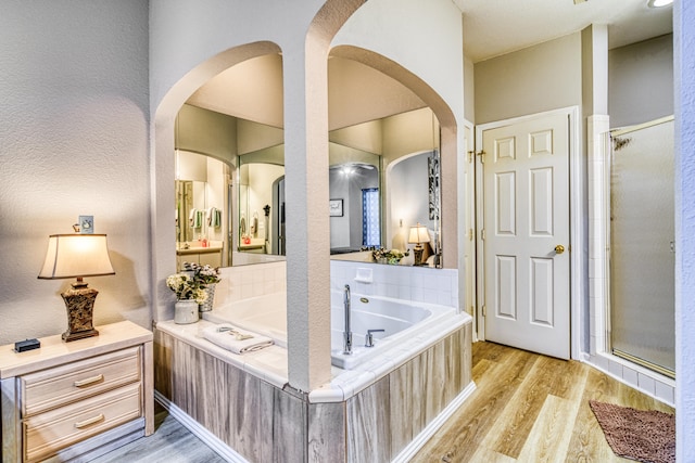 bathroom with wood-type flooring and shower with separate bathtub