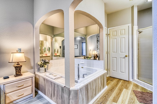bathroom featuring wood finished floors, a garden tub, and a stall shower