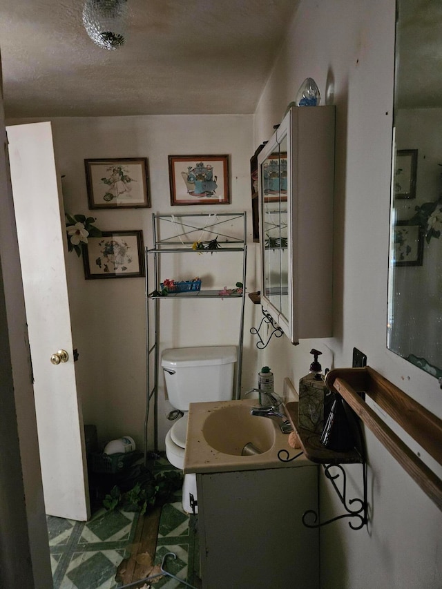 bathroom with vanity, toilet, and a textured ceiling