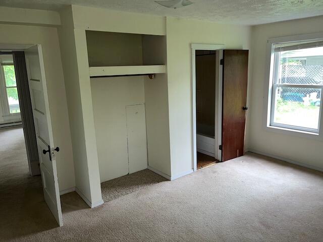 unfurnished bedroom with carpet floors, multiple windows, and a textured ceiling