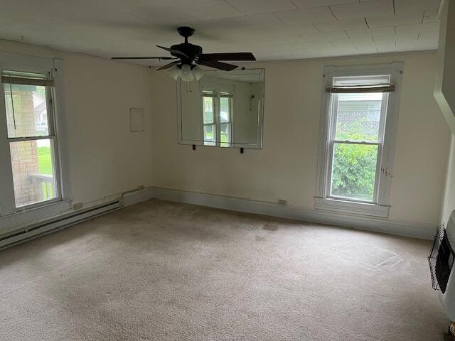 carpeted spare room with a healthy amount of sunlight, ceiling fan, and a baseboard radiator