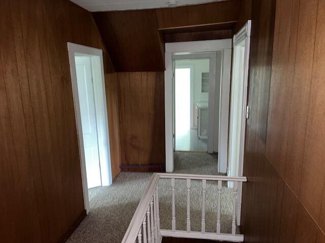 corridor with lofted ceiling, carpet flooring, and wooden walls