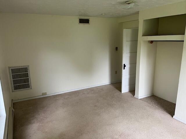 unfurnished bedroom with a closet, light colored carpet, and a textured ceiling