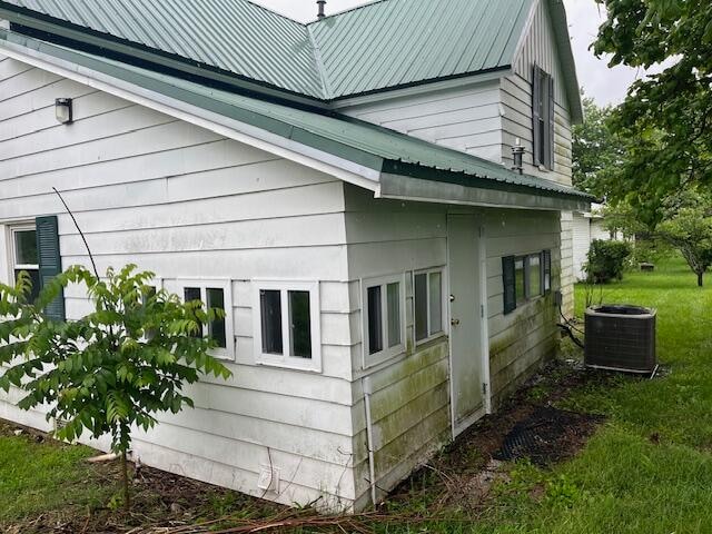 view of side of home featuring a yard and central AC