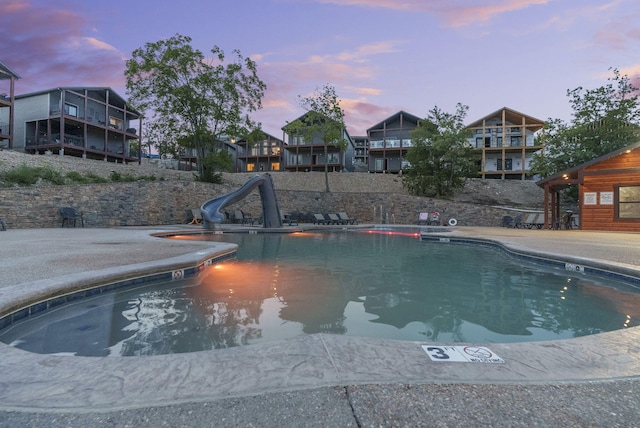 pool at dusk featuring a water slide