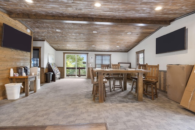 dining room featuring light carpet, vaulted ceiling with beams, wood walls, and wooden ceiling