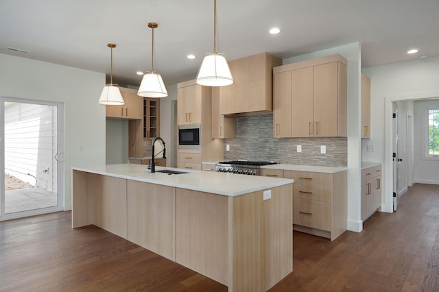 kitchen with decorative light fixtures, stove, sink, built in microwave, and light brown cabinets