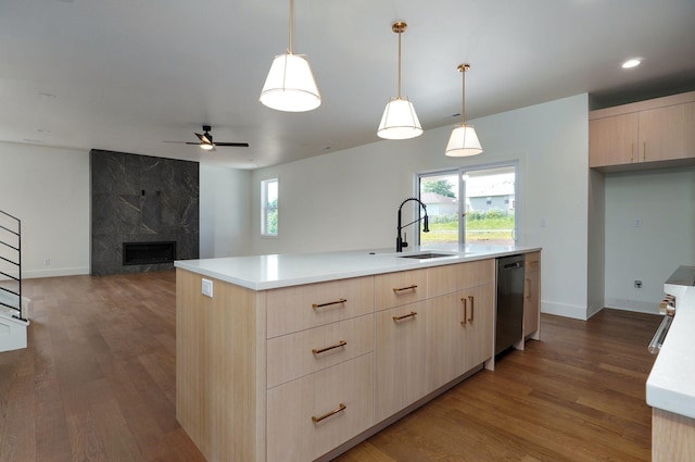 kitchen with sink, light brown cabinetry, dishwasher, a high end fireplace, and a center island