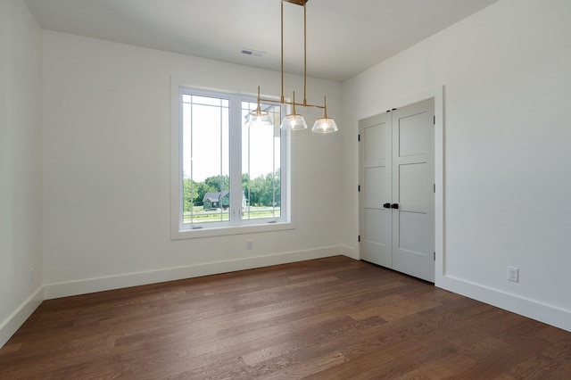 unfurnished room with an inviting chandelier and dark hardwood / wood-style flooring