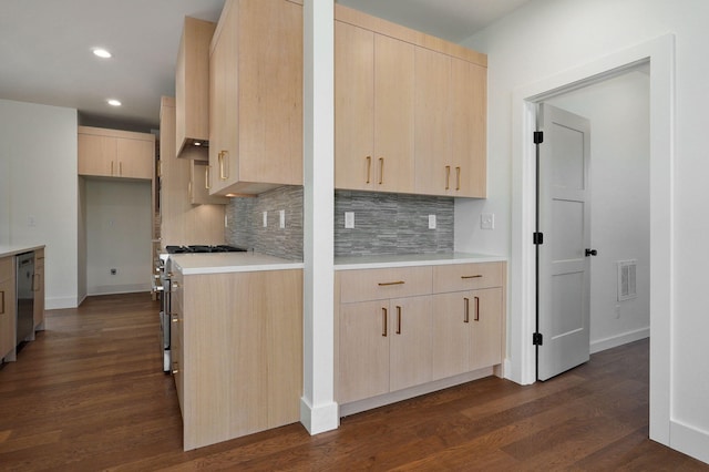 kitchen with dark wood-type flooring, light brown cabinetry, backsplash, and stainless steel appliances