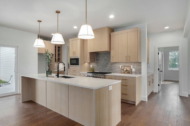 kitchen with decorative backsplash, light brown cabinetry, built in microwave, hanging light fixtures, and sink