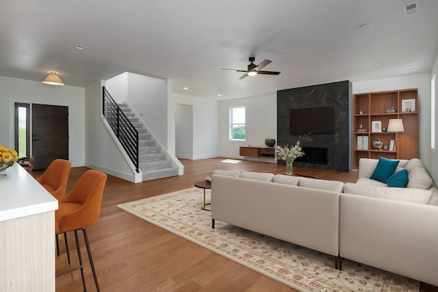 living room with ceiling fan, wood-type flooring, and a high end fireplace