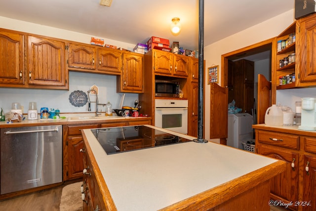 kitchen featuring sink, a kitchen island, stainless steel appliances, washing machine and dryer, and hardwood / wood-style floors