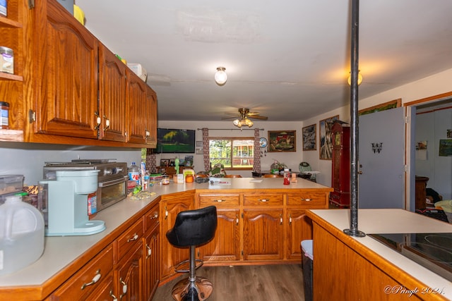 kitchen with ceiling fan, dark wood-type flooring, and kitchen peninsula