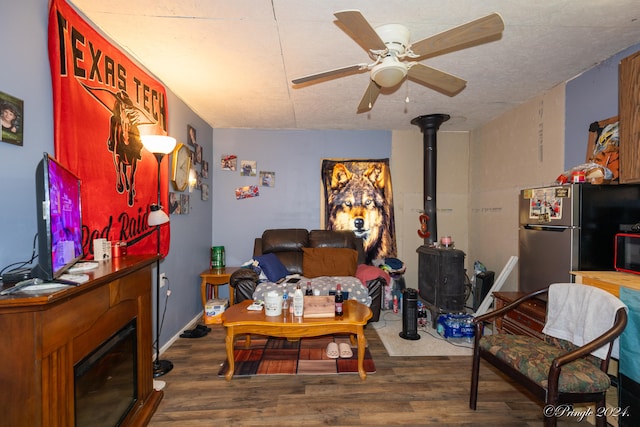 living room featuring a wood stove, ceiling fan, and wood-type flooring