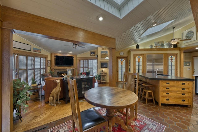 dining space featuring ceiling fan, vaulted ceiling with skylight, and plenty of natural light