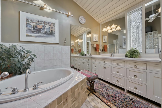 bathroom with tile patterned flooring, vanity, a chandelier, vaulted ceiling, and tiled bath