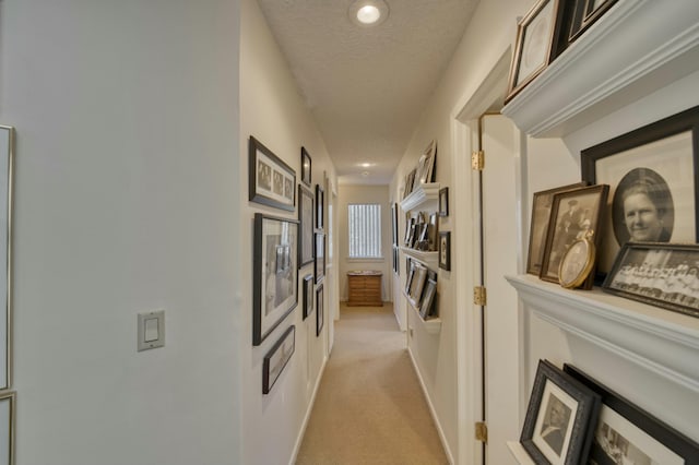 hall featuring light colored carpet and a textured ceiling