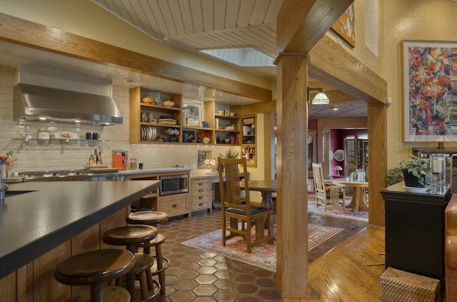 bar featuring backsplash, appliances with stainless steel finishes, and wall chimney range hood