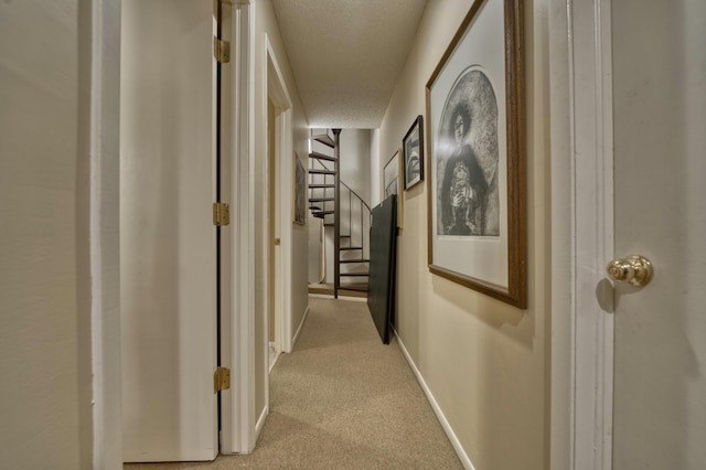 hall featuring light colored carpet and a textured ceiling