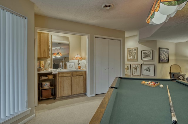 rec room featuring light carpet, billiards, sink, and a textured ceiling