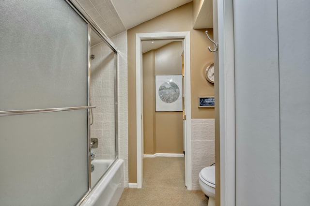 bathroom featuring vaulted ceiling, toilet, and bath / shower combo with glass door